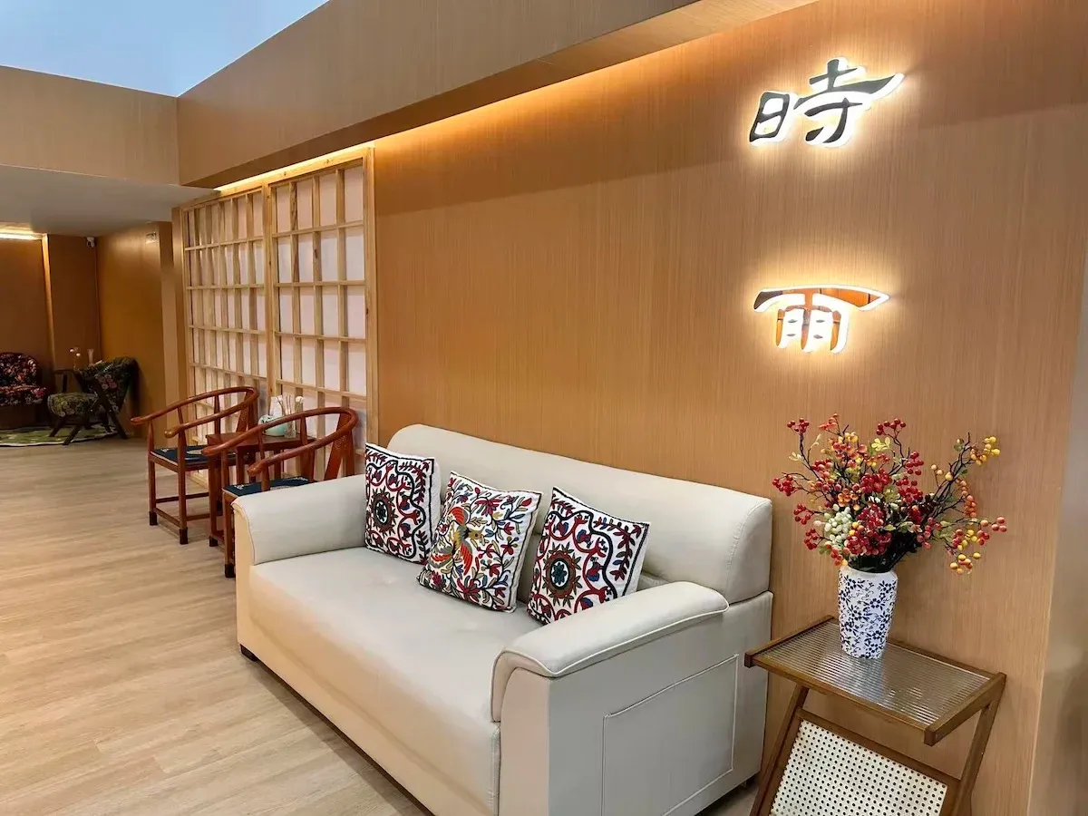 接待大廳,暖色木質牆面上有發光的「時雨」字樣,白色沙發與中式木椅